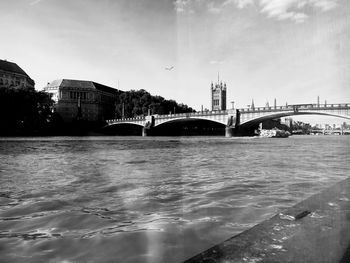 Bridge over river in city against sky