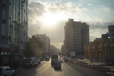 Cars on city street by buildings against sky