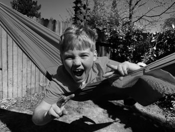 Young boy smiling in a hammock swing on a sunny day 