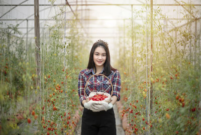 Portrait of smiling young woman standing against plants