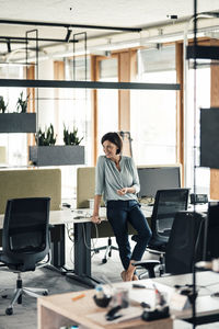 Female entrepreneur leaning on desk in office