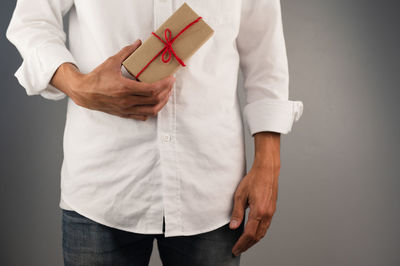 Midsection of man holding hands against white background