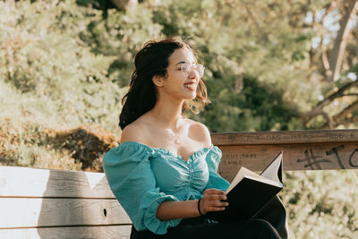 Young woman looking away while sitting on book