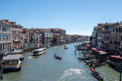 Boats in canal in city against clear sky