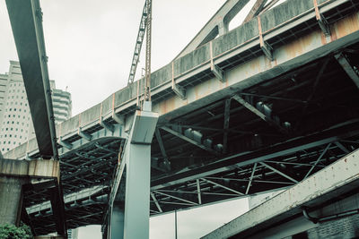 Low angle view of bridge by building against sky