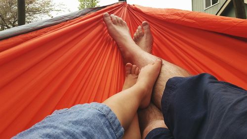 Low section of father with child relaxing on hammock