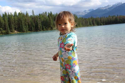 Portrait of cute girl holding mud while standing by lake