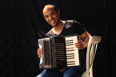 Portrait of smiling musician playing accordion on stage