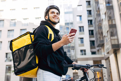 Full length of young man using smart phone in city