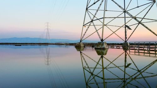 Electricity pylon against sky at sunset