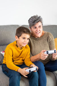 Portrait of mother and daughter sitting on sofa at home