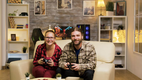 Portrait of smiling friends using laptop at home