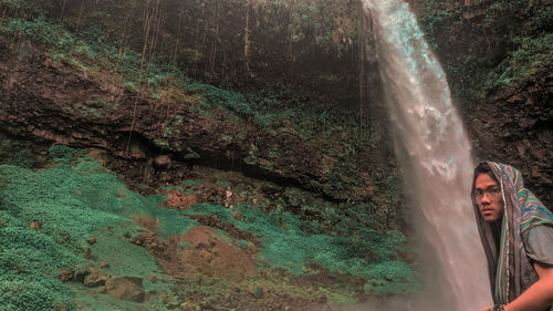 Portrait of man by waterfall in forest