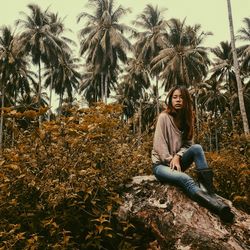 Young woman looking away while sitting on rock