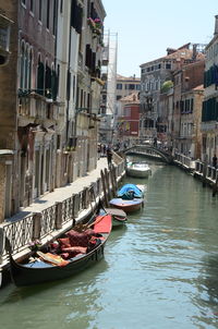 Boats moored in canal amidst buildings in city