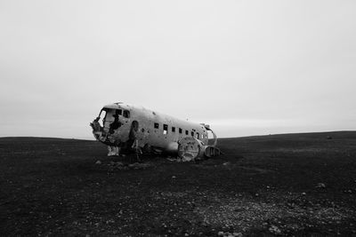 Abandoned airplane on land against sky