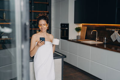 Portrait of young woman standing at home