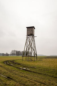 Water tower on field against sky