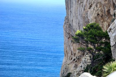 Rock formations by sea against blue sky