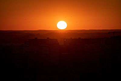 Silhouette buildings against sky during sunset