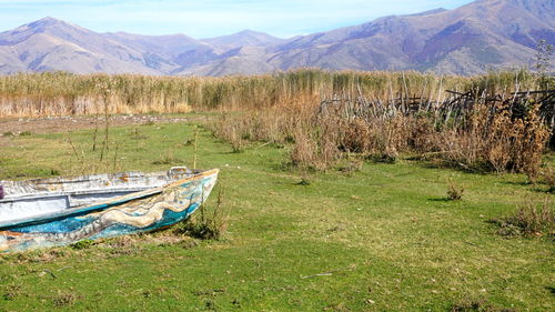 Abandoned boats on field against mountain range