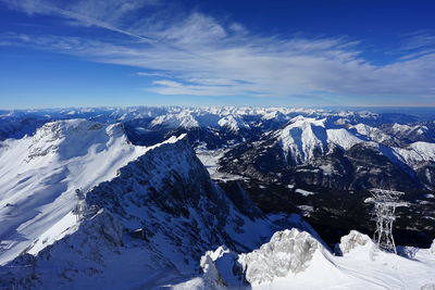 Aerial view of snowcapped mountains against blue sky