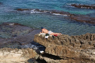 High angle view of shirtless man on rock at beach