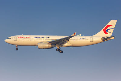 Low angle view of airplane flying against clear blue sky