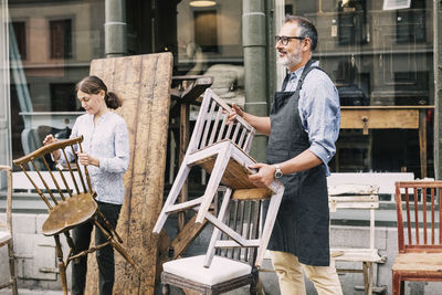 Business owners holding chairs while arranging outside store