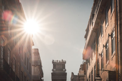 Low angle view of sunlight streaming through buildings