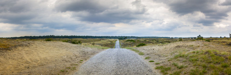 Road amidst field against sky