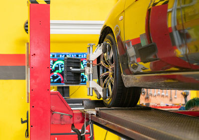 Car mechanic installing sensor during wheel alignment adjustment at repair service station