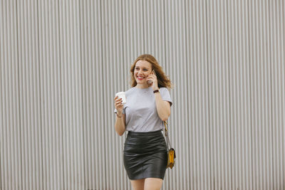 Smiling woman talking on phone while walking in city
