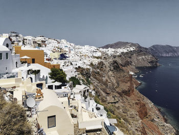 High angle view of townscape by sea against clear blue sky