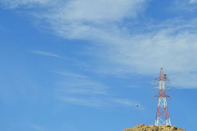 Low angle view of electricity pylon against blue sky