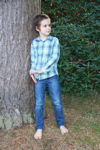 Portrait of boy standing on tree trunk