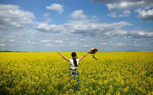 Rear view of woman walking on field against sky