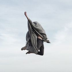 Low angle view of man jumping against sky