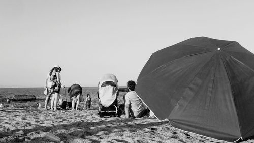 Rear view of people standing on sand dune against clear sky