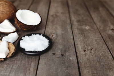 Broken coconuts on gray wooden background. white coconut fresh pulp on black plate
