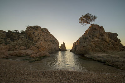 Rock formation on sea against clear sky