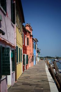 View of residential buildings by sea against clear sky