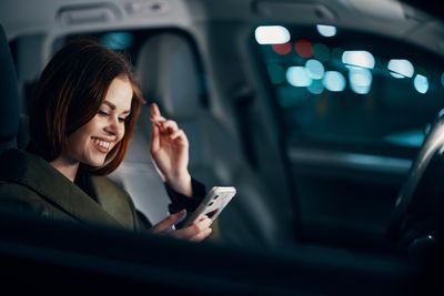 Portrait of young woman using mobile phone in car