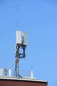 Low angle view of communications tower against clear blue sky