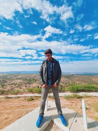 Full length of young man standing on land against sky