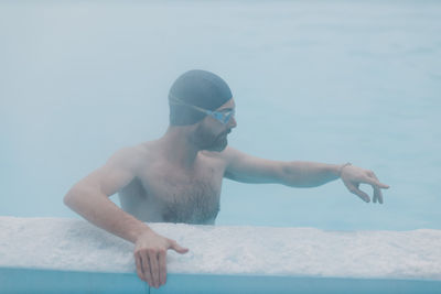 Rear view of man with arms raised in swimming pool