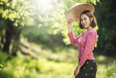 Young woman wearing hat standing against trees