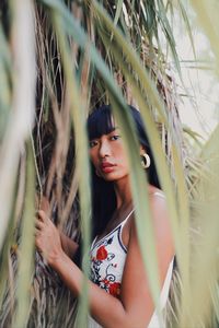 Portrait of young woman standing against plants