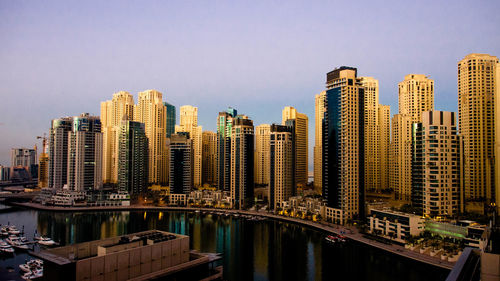 Modern buildings by river against sky in city