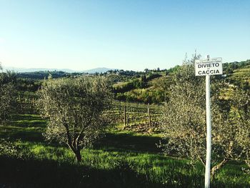 Road sign on field against sky